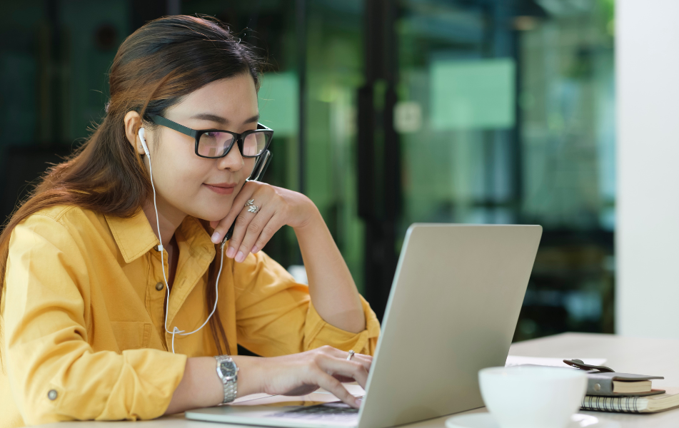 Une jeune femme, l'air concentré, suit une formation digitale sur son PC. 